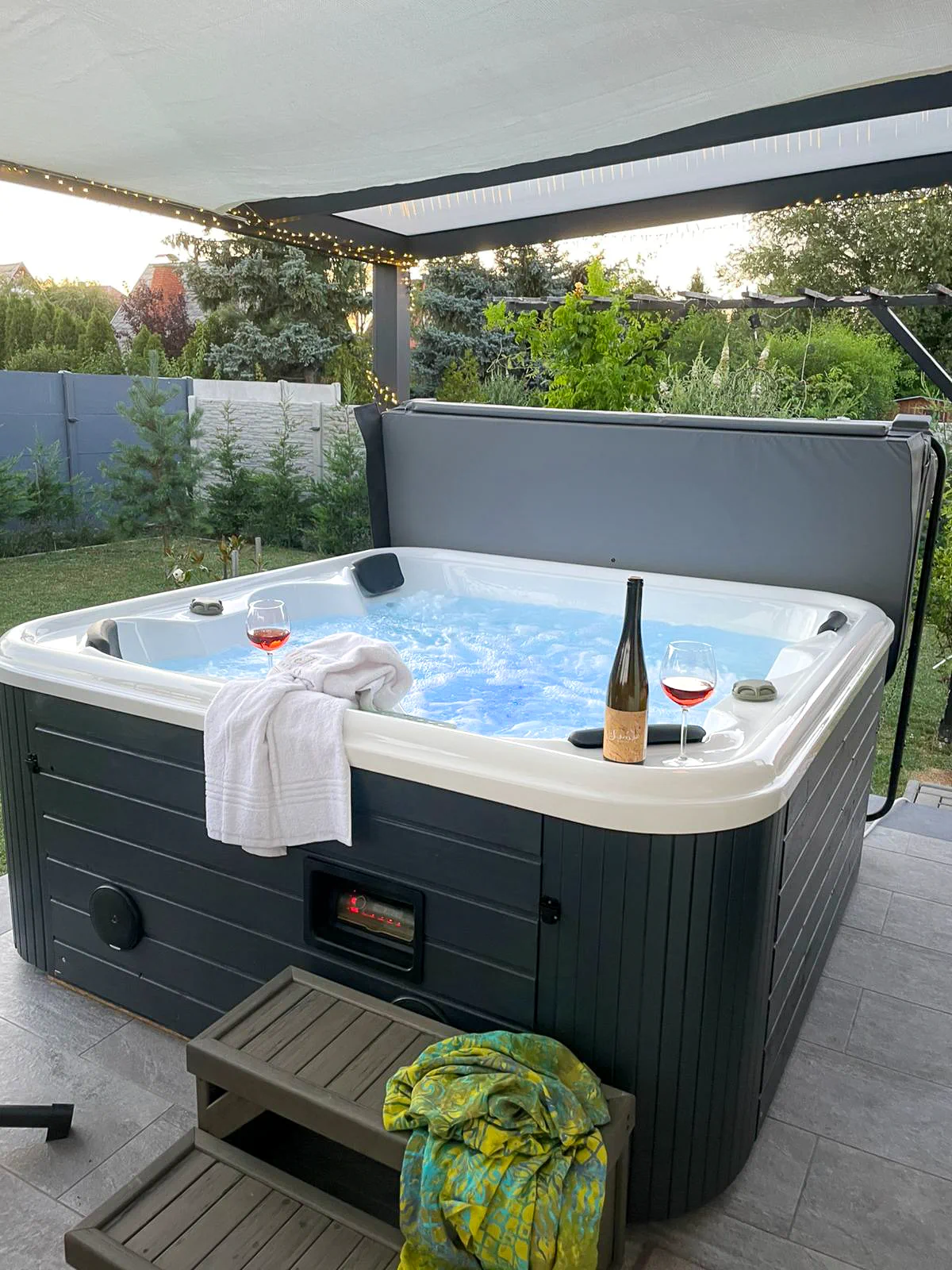 Fedett teraszon elhelyezett jakuzzi két borospohárral, borral és törölközőkkel