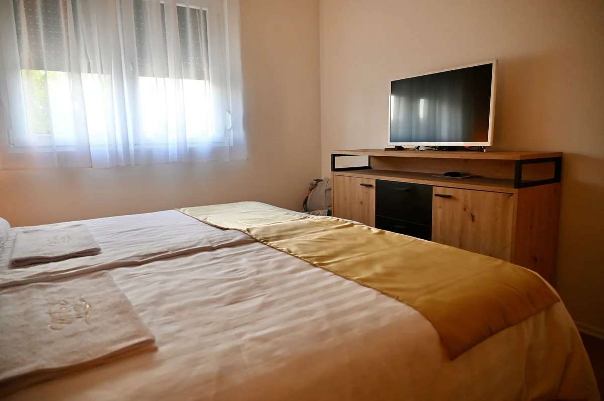 Hálószoba televízióval, fa bútorokkal és meleg hangulatfényekkel