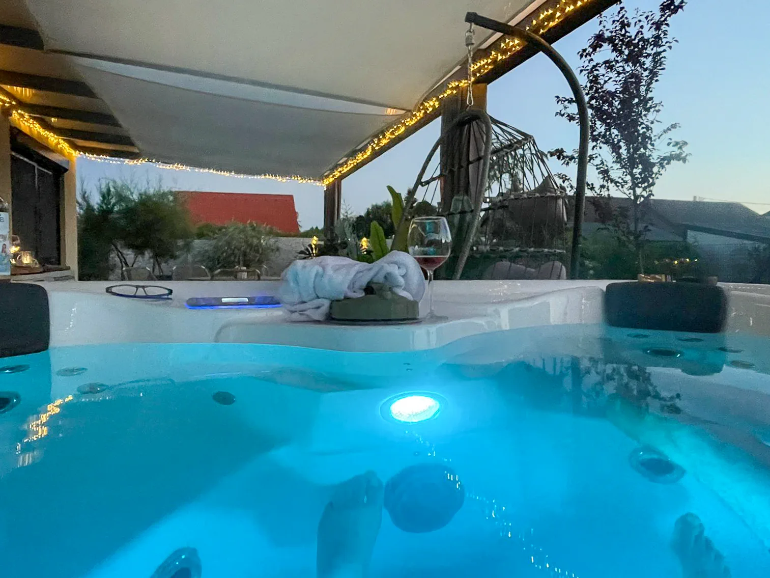 Jakuzzi a fedett teraszon, esti fényekkel és borospohárral