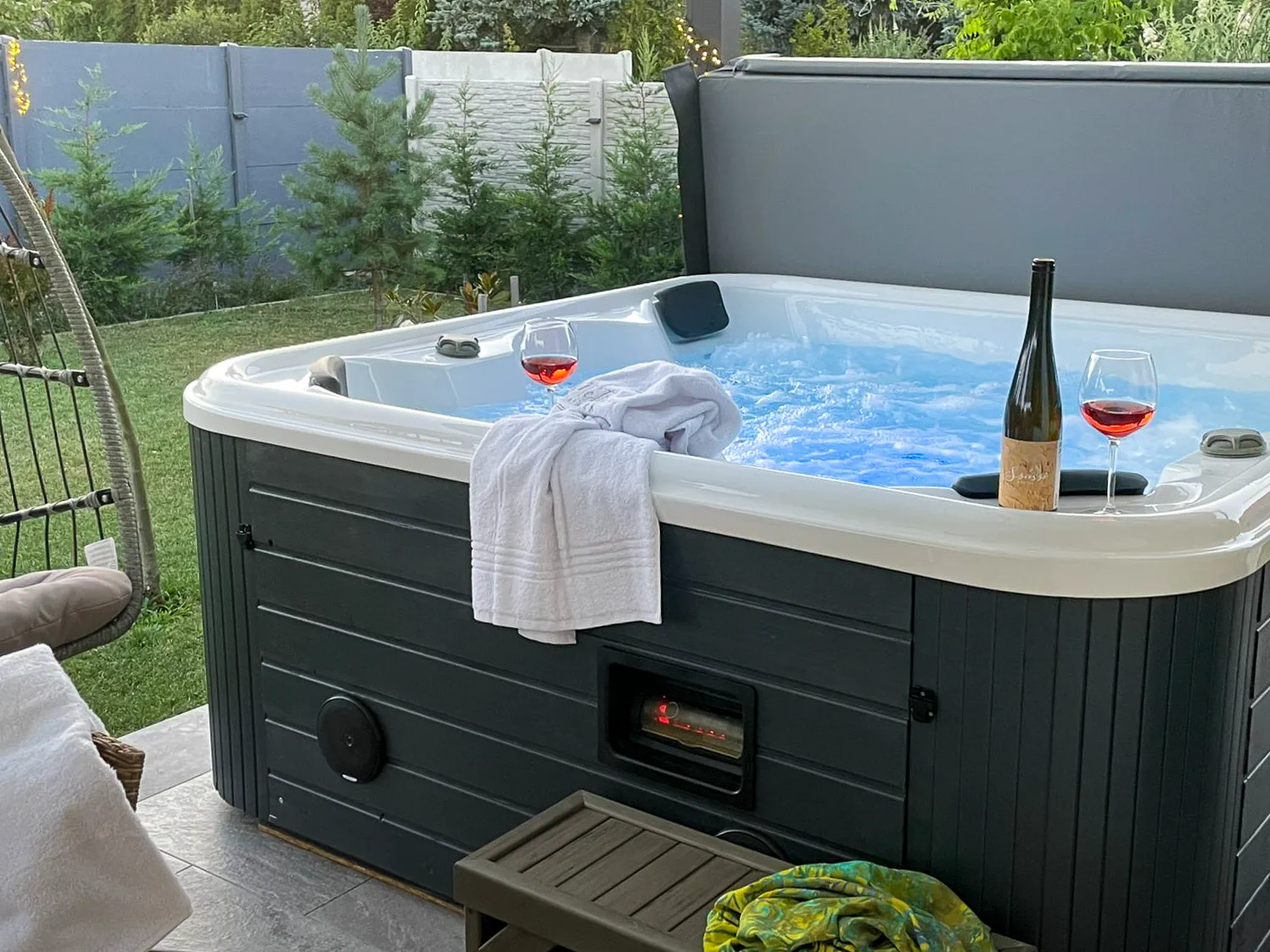 Jakuzzi két borospohárral, törölközőkkel és kerti függőfotellel