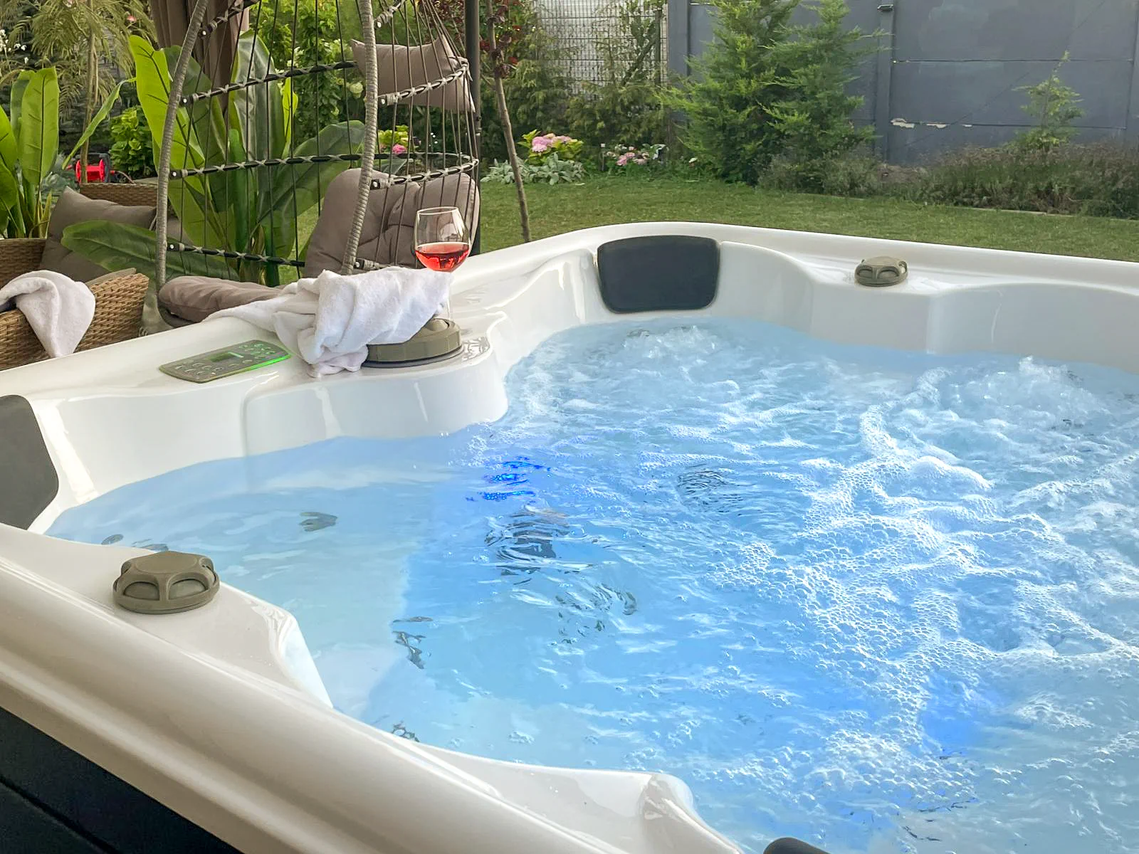 Jakuzzi működő masszázsfúvókákkal, borospohárral és kerti kilátással